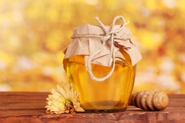 Jar of honey and wooden drizzler on table on yellow background — Stock Photo, Image