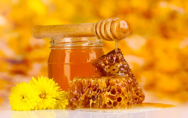 罐蜂蜜、 蜂窝和黄色背景上的木制 drizzler — 图库照片