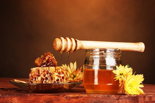 Glas Honig, Waben und hölzerner Nieselregen auf dem Tisch auf gelbem Hintergrund — Stockfoto