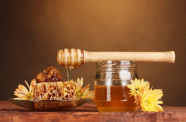 Jarra de mel, favos de mel e drizzler de madeira na mesa sobre fundo amarelo — Fotografia de Stock