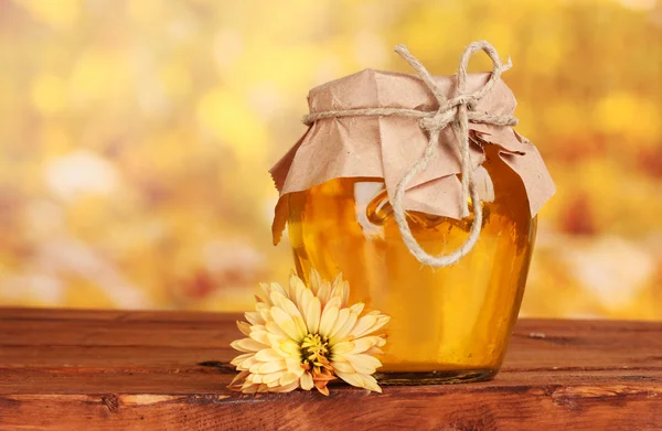 Vaso di miele su tavolo di legno su sfondo giallo — Foto Stock