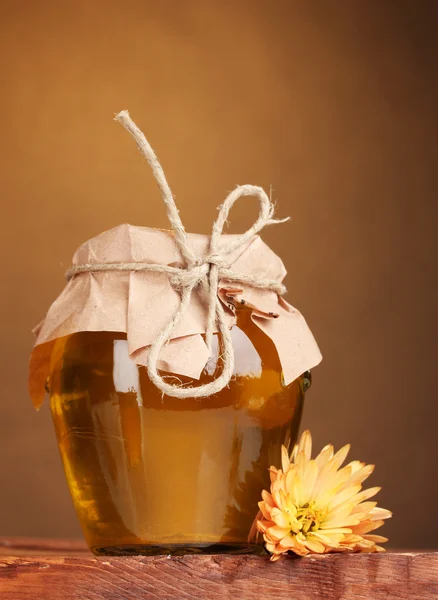 Vaso di miele su tavolo di legno su sfondo giallo — Foto Stock