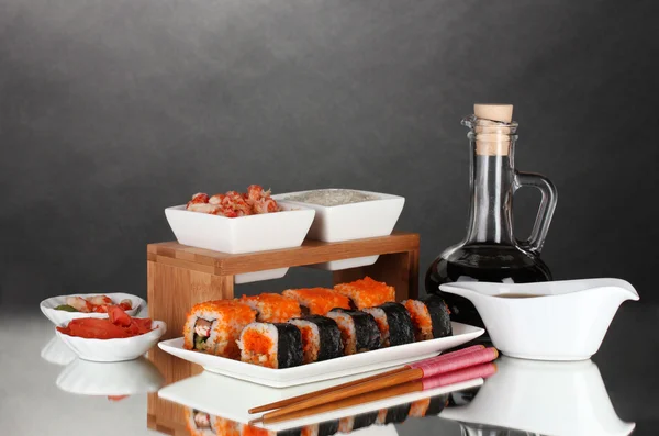 Delizioso sushi su piatto, bacchette, salsa di soia, pesce e gamberetti su b grigio — Foto Stock