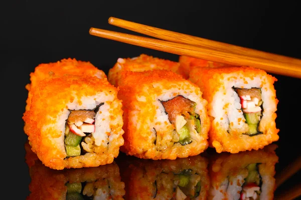 Heerlijke sushi en eetstokjes op zwarte achtergrond — Stockfoto