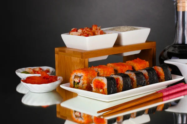 Heerlijke sushi op plaat, eetstokjes, sojasaus, vis en garnalen op grijze b — Stockfoto