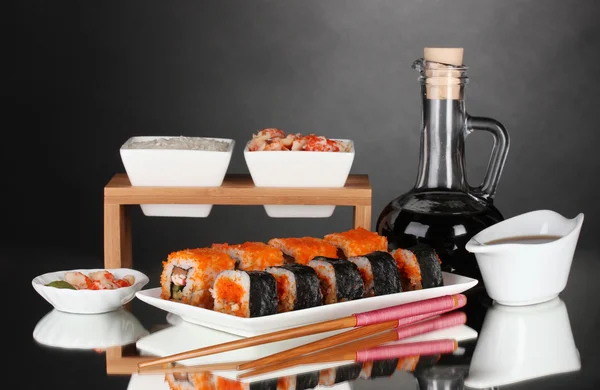 Heerlijke sushi op plaat, eetstokjes, sojasaus, vis en garnalen op grijze b — Stockfoto