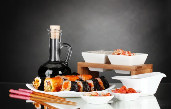 Delicious sushi on plate, chopsticks, soy sauce, fish and shrimps on gray b — Stock Photo, Image