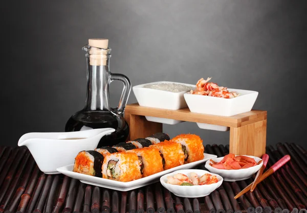 Köstliches Sushi auf Teller, Essstäbchen, Sojasauce, Fisch und Garnelen auf Bambus — Stockfoto