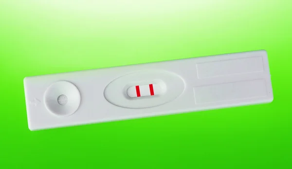Положительный тест на беременность на зеленом фоне — стоковое фото