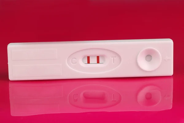 Teste de gravidez positivo em fundo rosa — Fotografia de Stock