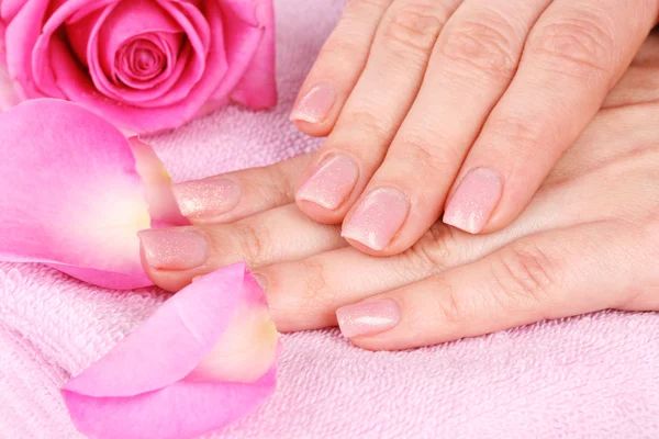 Roze handdoek met rozen en handen close-up — Stockfoto