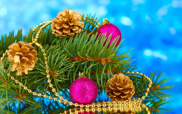 Groene kerstboom met speelgoed en kegels op blauw — Stockfoto