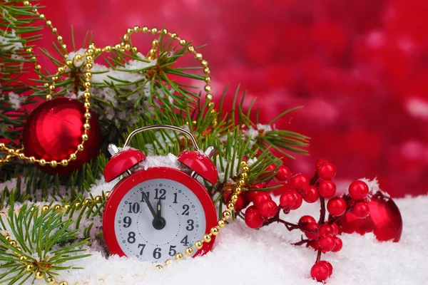 Albero di Natale verde con giocattolo e orologio sulla neve su rosso — Foto Stock