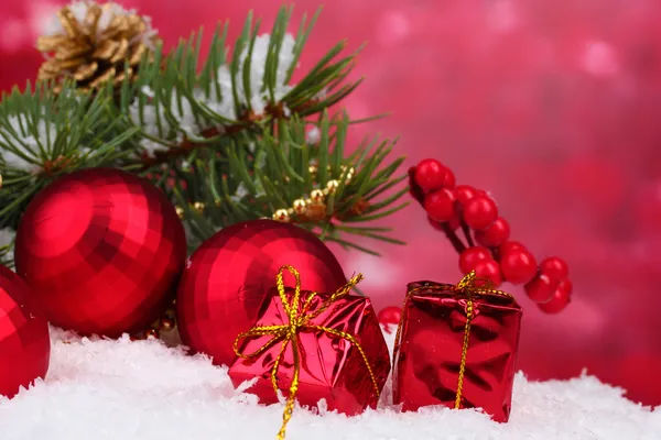 Christmas ball and green tree in the snow on red — Stock Photo, Image