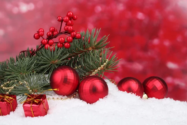 Christmas ball and toy with green tree in the snow on red — Stock Photo, Image