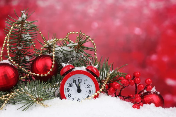 Green Christmas tree with toy and clock in the snow on red — Stock Photo, Image