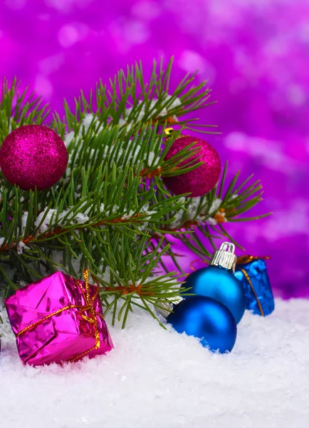 Kerstmis bal en speelgoed met groene boom in de sneeuw op paars — Stockfoto