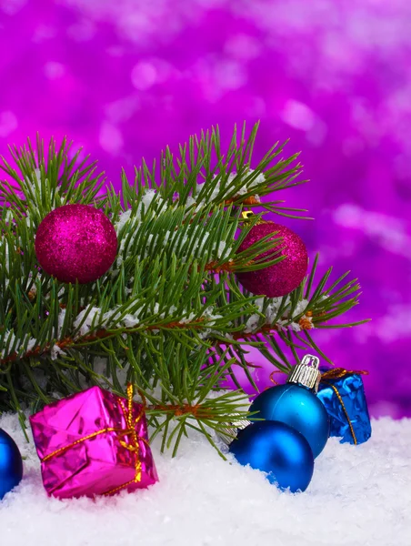Різдвяний м'яч та іграшка з зеленим деревом у снігу на фіолетовому — стокове фото
