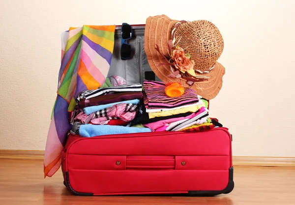 Открытый красный чемодан с одеждой в номере — стоковое фото
