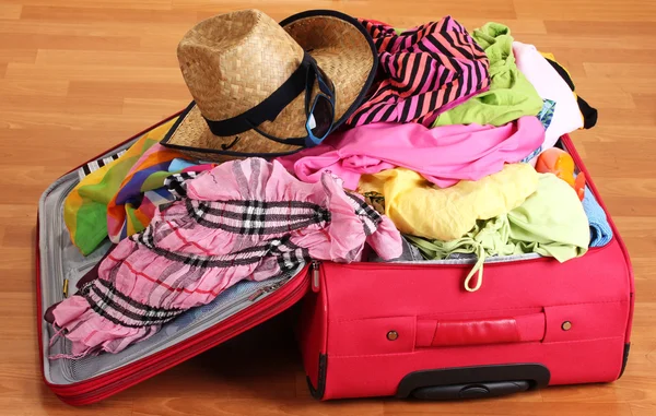 Valigia rossa aperta con indumenti in camera — Foto Stock