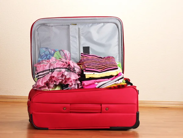 Відкрита червона валіза з одягом у кімнаті — стокове фото