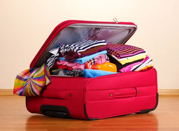 Открытый красный чемодан с одеждой в номере — стоковое фото