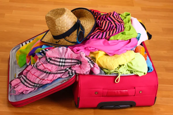 Offener roter Koffer mit Kleidung im Zimmer — Stockfoto