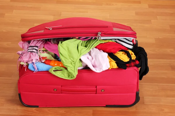 Красный чемодан с одеждой в номере — стоковое фото