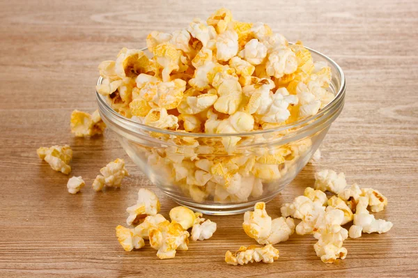 Popcorn in glazen kom op houten tafel — Stockfoto