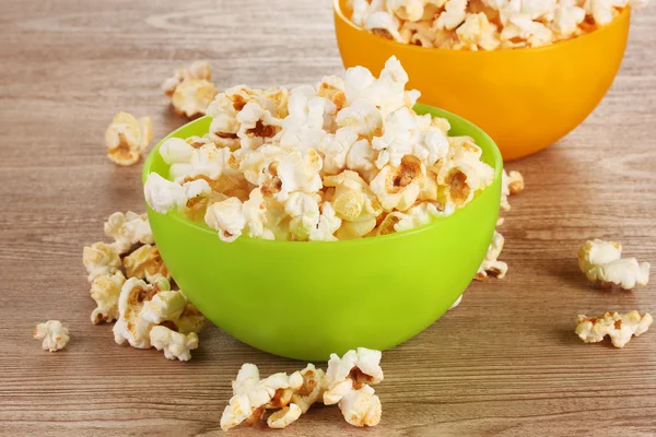 Popcorn w jasnej plastikowych misek na drewnianym stole — Zdjęcie stockowe