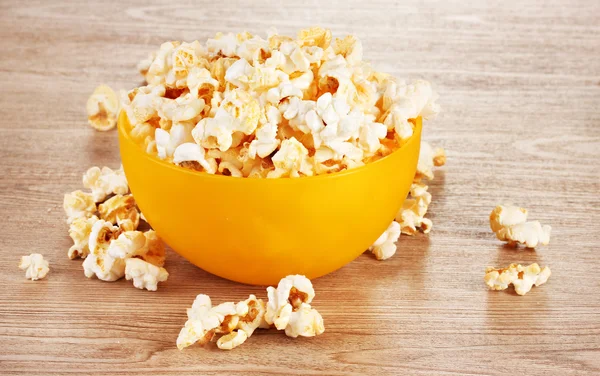 Popcorn in bright plastic bowl on wooden table — Stock Photo, Image