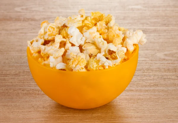 Popcorn in bright plastic bowl on wooden table — Stock Photo, Image