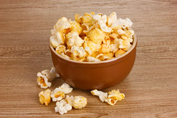 Popcorn i brun skål på träbord — Stockfoto