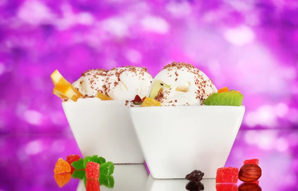 Leckeres Vanilleeis mit Schokolade und Früchten in Schalen auf lila Ba — Stockfoto