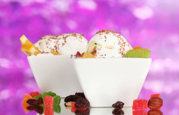 Leckeres Vanilleeis mit Schokolade und Früchten in Schalen auf lila Ba — Stockfoto