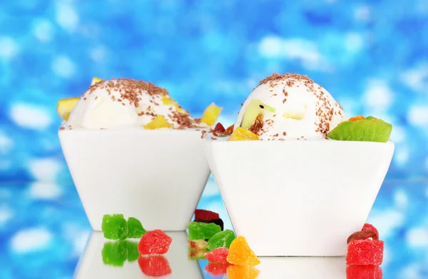 Вкусное ванильное мороженое с шоколадом и фруктами в мисках на синей спине — стоковое фото