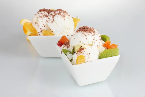 Heerlijk vanille-ijs met chocolade en fruit in kommen geïsoleerd op — Stockfoto