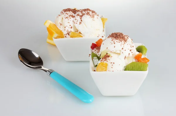Delicioso sorvete de baunilha com chocolate e frutas em tigelas e colher é — Fotografia de Stock