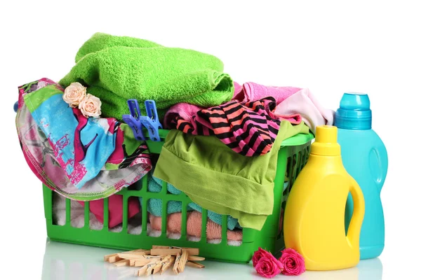 用的洗涤剂和孤立在白纸上的绿色塑料篮子里的衣服 — 图库照片