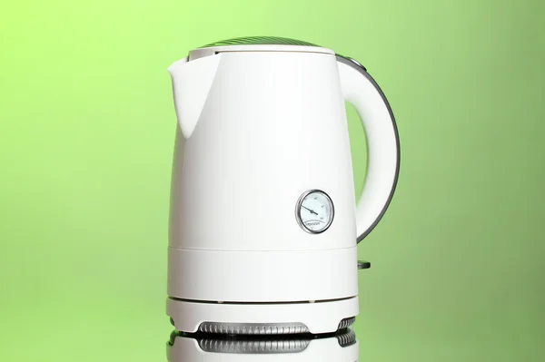 stock image White electric kettle on green