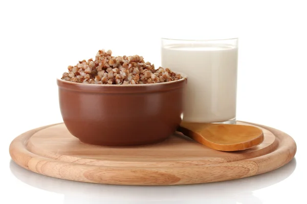 Boiled buckwheat in a brown bowl a glass of milk on a wooden board isolated — Stock Photo, Image