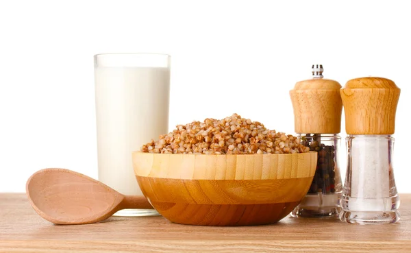 Trigo sarraceno hervido en un tazón de madera con un vaso de leche sobre una mesa de madera isol —  Fotos de Stock