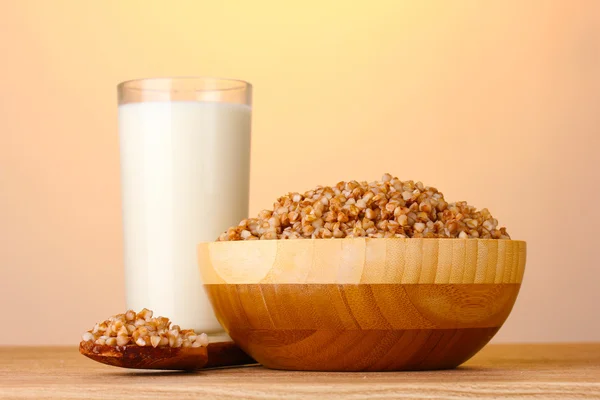 Grano saraceno bollito in una ciotola di legno con un bicchiere di latte su tavolo di legno su b — Foto Stock