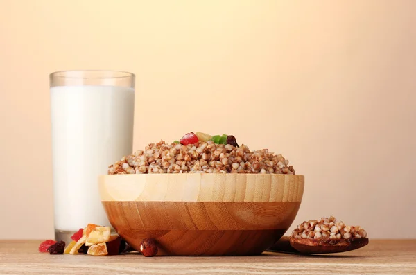 Boiled buckwheat in a wooden bowl with a glass of milk on wooden table on b — Stock Photo, Image