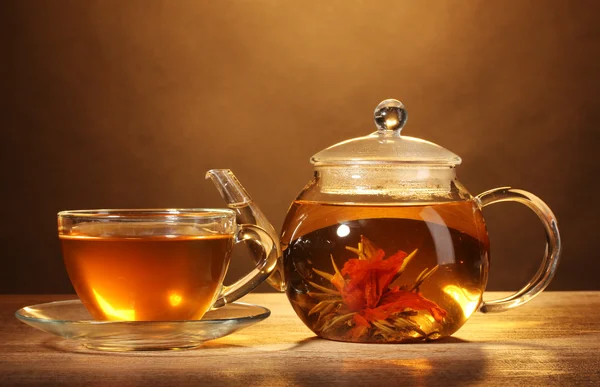 Bule de vidro e xícara com chá verde exótico na mesa de madeira no backgro marrom — Fotografia de Stock