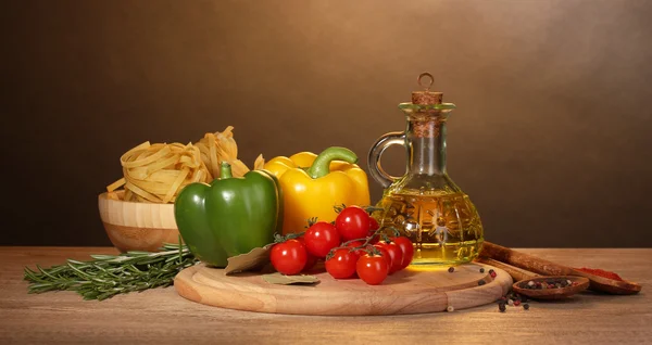 Nudlar i skål, burk med olja, kryddor och grönsaker på träbord på brown — Stockfoto