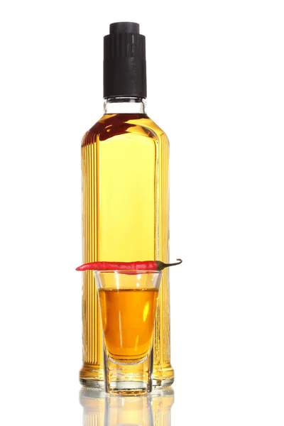 Бутылка и стакан водки перец и красный перец чили изолированы на белом — стоковое фото