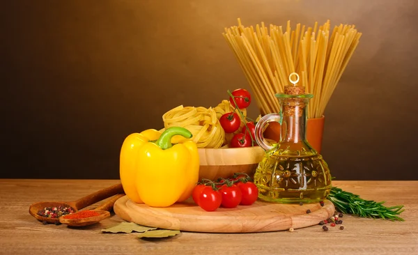 Spaghetti noedels in kom, pot van olie en groenten op houten tafel op br — Stockfoto