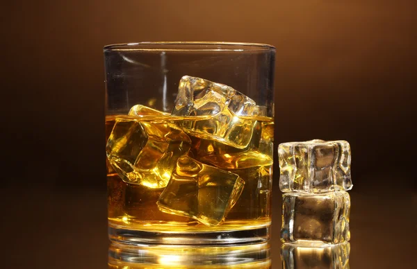 Glas whisky en ijs op bruine achtergrond — Stockfoto