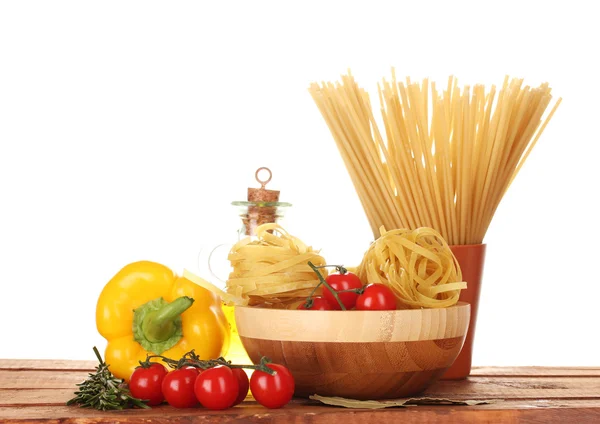 Spaghetti, nudlar i skål, burk med olja och grönsaker på träbord isola — Stockfoto